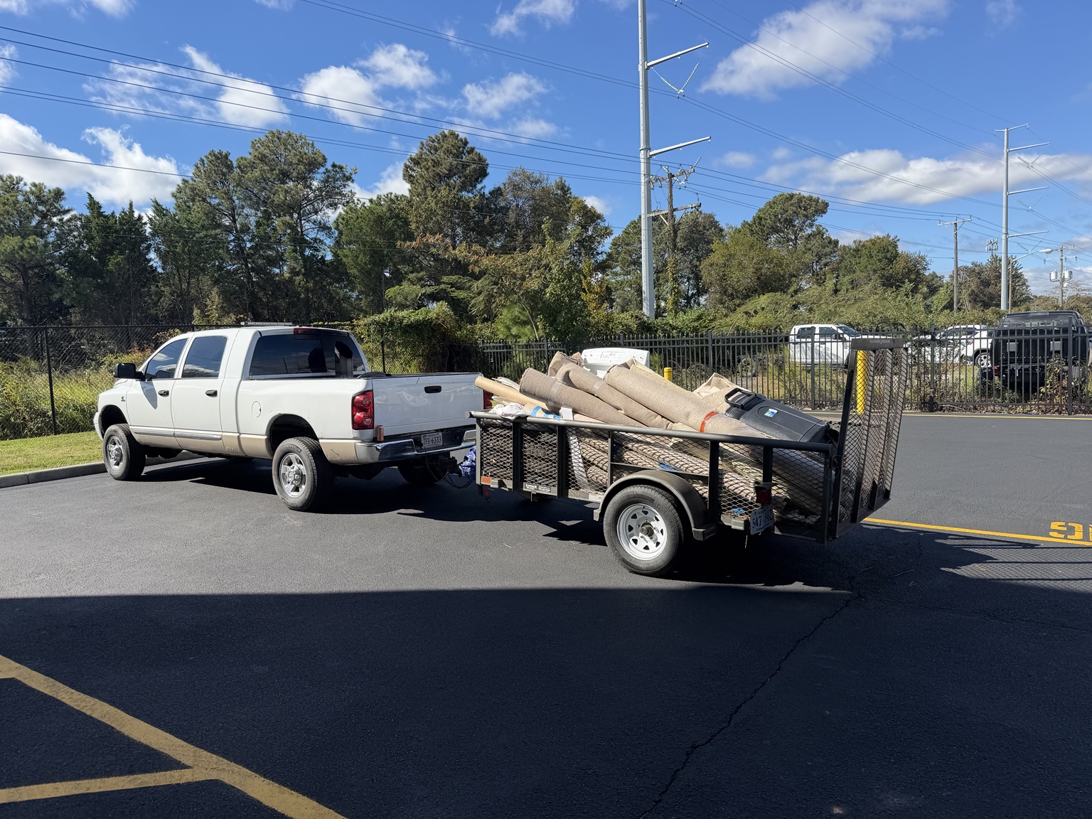 Pickup truck and utility trailer loaded with old carpet and unwanted items for haul-away
